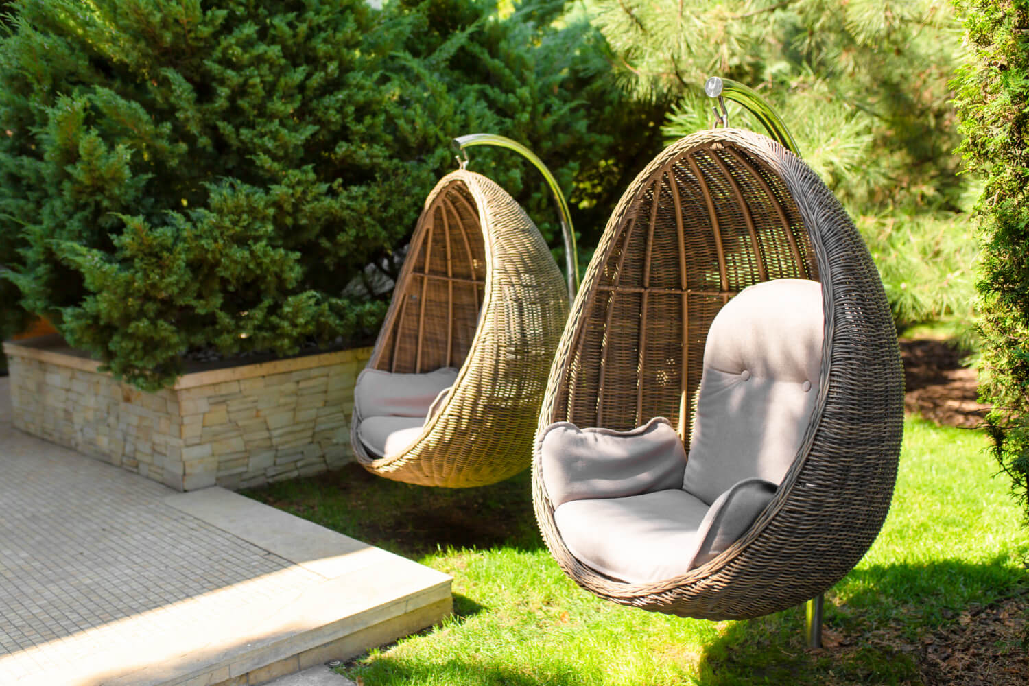 hanging wicker egg shaped chairs with cushions in back yard